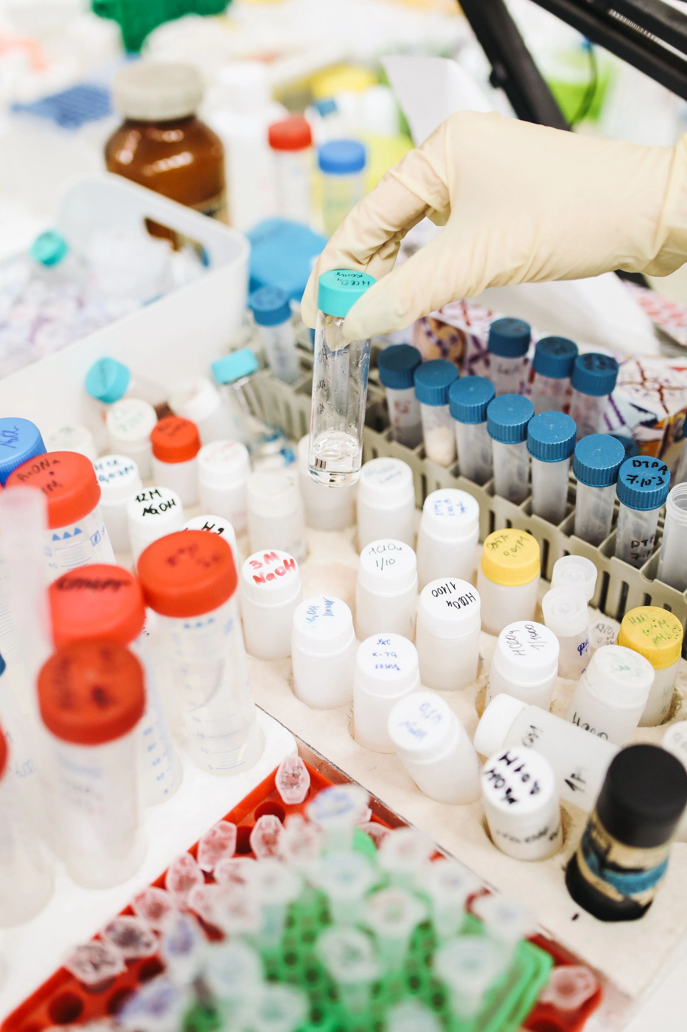 Mão enluvada segurando tubos de amostras em laboratório; imagem ilustrativa